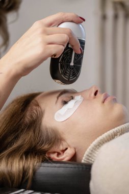 Kirpik uzatma prosedürü. Bir kız için kirpik uzatma yapan bir kadın.