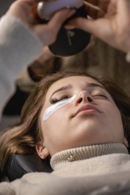 Kirpik uzatma prosedürü. Bir kız için kirpik uzatma yapan bir kadın.