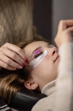 Kirpik uzatma prosedürü. Bir kız için kirpik uzatma yapan bir kadın.