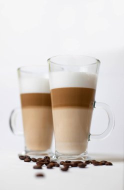 Kahve çekirdekleri ile çevrili beyaz arka planda latte macchiato. Beyaz arka planda Latte macchiato.