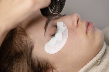 Kirpik uzatma prosedürü. Bir kız için kirpik uzatma yapan bir kadın.