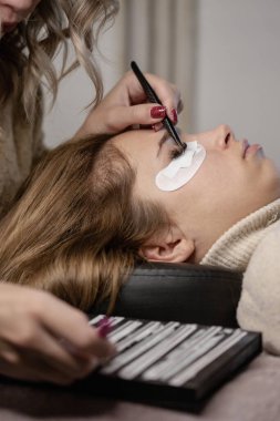 Kirpik uzatma prosedürü. Bir kız için kirpik uzatma yapan bir kadın.