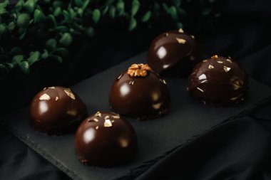 Çikolata jöleli, altın serpiştirilmiş lezzetli kremalı kekler. Karanlık bir arka planda leziz bir krema..