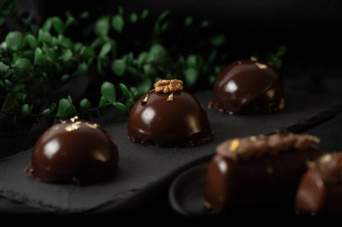 Çikolata jöleli, altın serpiştirilmiş lezzetli kremalı kekler. Karanlık bir arka planda leziz bir krema..