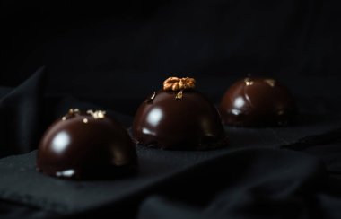 Çikolata jöleli, altın serpiştirilmiş lezzetli kremalı kekler. Karanlık bir arka planda leziz bir krema..