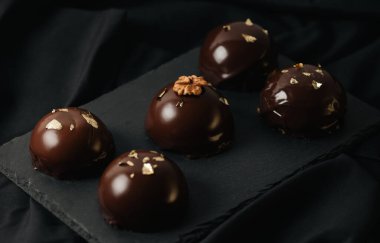 Çikolata jöleli, altın serpiştirilmiş lezzetli kremalı kekler. Karanlık bir arka planda leziz bir krema..