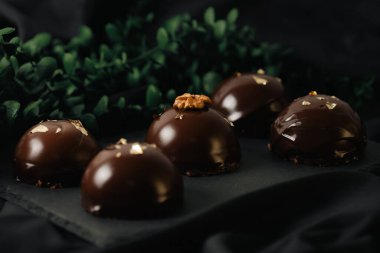 Çikolata jöleli, altın serpiştirilmiş lezzetli kremalı kekler. Karanlık bir arka planda leziz bir krema..