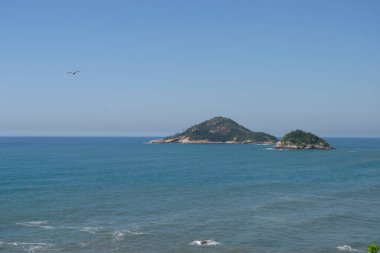 Rio de Janeiro şehrinde yer alan Praia de Grumari 'nin berrak mavi sularıyla dağlar, bitki örtüsü ve okyanus..