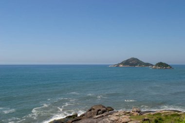 Rio de Janeiro şehrinde yer alan Praia de Grumari 'nin berrak mavi sularıyla dağlar, bitki örtüsü ve okyanus..