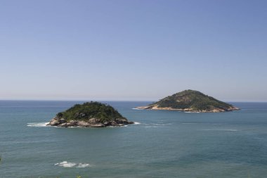 Rio de Janeiro şehrinde yer alan Praia de Grumari 'nin berrak mavi sularıyla dağlar, bitki örtüsü ve okyanus..
