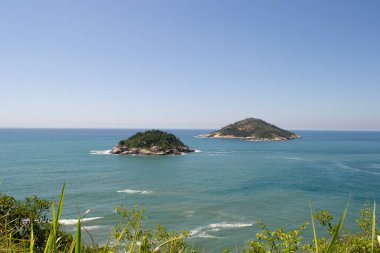 Rio de Janeiro şehrinde yer alan Praia de Grumari 'nin berrak mavi sularıyla dağlar, bitki örtüsü ve okyanus..