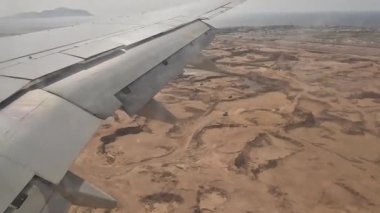 Uçak. Uçuş ve Seyahat, uçağın kanat penceresinden manzara. Ağır çekim. Uçak penceresinden bak. Kanatta uçarken cam uçağından bakıyor..