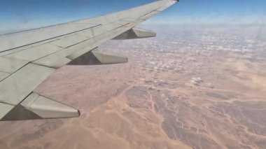 Uçak. Uçuş ve Seyahat, uçağın kanat penceresinden manzara. Ağır çekim. Uçak penceresinden bak. Kanatta uçarken cam uçağından bakıyor..