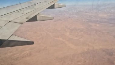 Uçak. Uçuş ve Seyahat, uçağın kanat penceresinden manzara. Ağır çekim. Uçak penceresinden bak. Kanatta uçarken cam uçağından bakıyor..