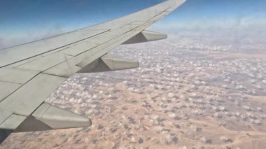 Uçak. Uçuş ve Seyahat, uçağın kanat penceresinden manzara. Ağır çekim. Uçak penceresinden bak. Kanatta uçarken cam uçağından bakıyor..