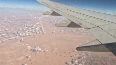 Uçak. Uçuş ve Seyahat, uçağın kanat penceresinden manzara. Ağır çekim. Uçak penceresinden bak. Kanatta uçarken cam uçağından bakıyor..