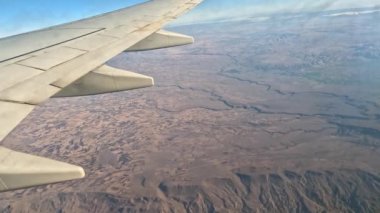 Uçak. Uçuş ve Seyahat, uçağın kanat penceresinden manzara. Ağır çekim. Uçak penceresinden bak. Kanatta uçarken cam uçağından bakıyor..