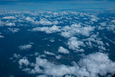 Aerial view of an airplane flying above clouds and sky. View from the plane window.