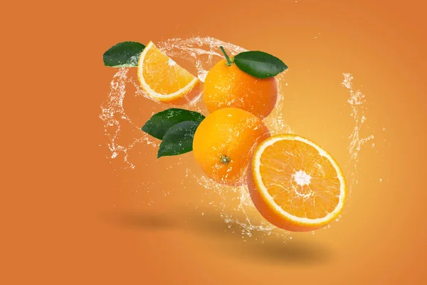 オレンジの背景に新鮮なスライスされたオレンジとオレンジの果実に水が飛び散る ストック画像