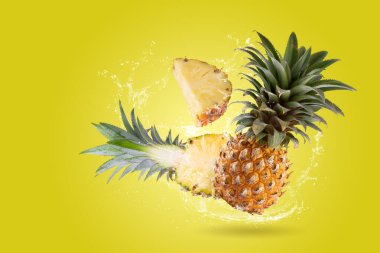 Sarı arka planda izole edilmiş, bölünmüş ananas meyvesine su sıçraması.