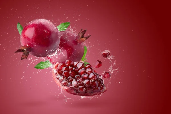 新鮮なザクロの果実と水で作られた創造的なレイアウト赤を背景にスプラッシング ロイヤリティフリーのストック写真