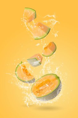 Portakal rengi Japon kavunlarından ya da kavunlardan ve portakal arkaplanına sıçrayan sudan oluşan yaratıcı bir düzen.