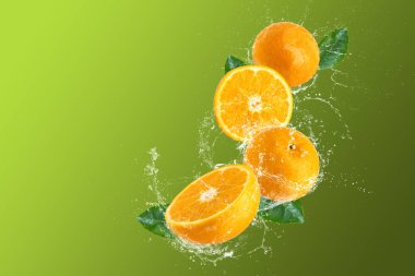 Yeşil zemin üzerine serpilen portakal ve portakal meyveleri ve sudan oluşan yaratıcı bir düzen.