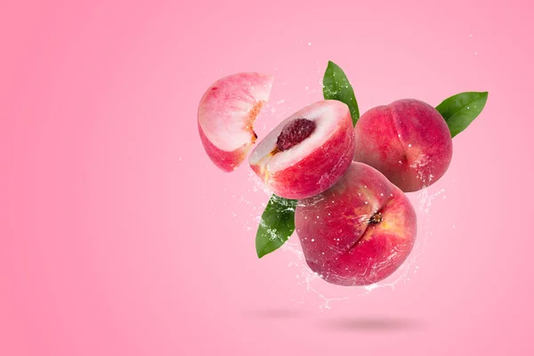 stock image Creative layout made from whole and slice of Ripe juicy peaches fruit and water Splashing on a pink background