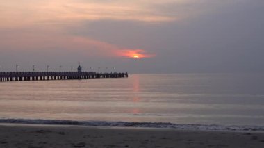 Gün doğumunda sahile doğru uzanan bir köprü.