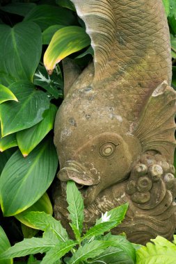 Bahçeyi süslemek için balık heykeli ve bahçeyi süslemek için güzel ağaçlar ve yapraklar..