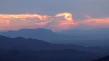 Majestic 'in günbatımı ya da gün doğumu manzarası. Dağın tepesinde ışık ışınları ve bulutlar, kara bulutların arasında parlayan ışık ışınları. Renkli dramatik gökyüzü ile gün batımı.