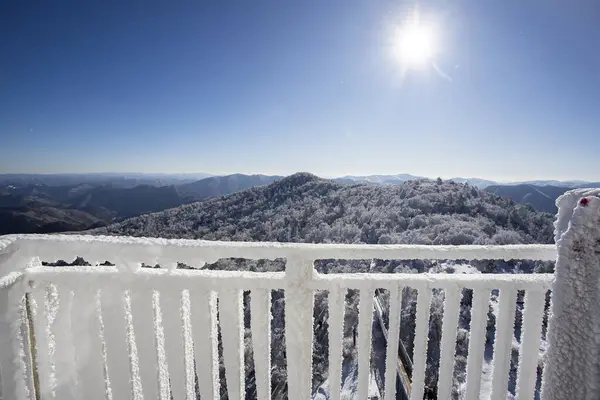 stock image The balcony railing is covered with frost with snow-white background. View from the balcony during a snowfall. Selective focus.