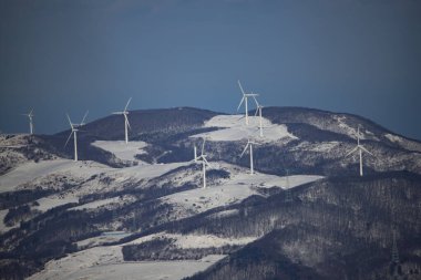 Güney Kore 'nin Gangwon Eyaleti Hoengseong İlçesi' ndeki Taegi Dağı 'nın karla kaplı zirvesinde bir rüzgar türbininin uzaktan görüntüsü..