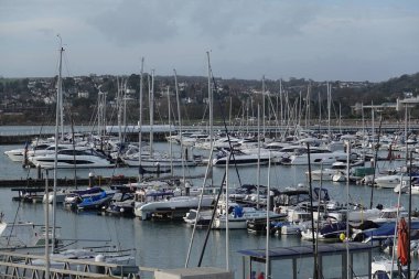 Gemiler gökyüzünün altında dalgalı renkler, kayalık kıyılar ve batan güneş ile süzülüyor.