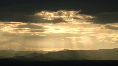 Zaman atlamalı video 4K hareketi, dağlarda gün batımı güneş ışınları ve bulutlarla
