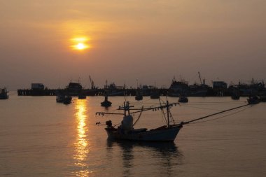 Balıkçı teknesi huzurlu sularda dinleniyor ve Sunset 'te dramatik bulutlar var.