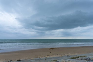 Pofuduk bulutlar, tropikal bir plajın üzerinde, kıyı şeridinde turkuaz dalgalar eşliğinde parlak bir yaz gökyüzünde sürükleniyor.