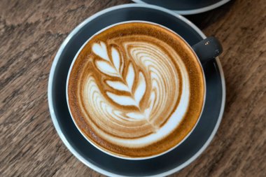 Ahşap bir masada kahve fincanı. Sahne sıcacık, sıcak içeceklerin yakın çekimleri ve zengin kahverengi tonlarıyla.