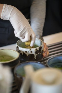 Çay seremonisi için geleneksel aksesuarlarla kibrit tozu çeken bir kadın.