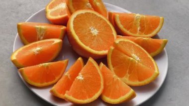 Dilimlenmiş portakallar beyaz bir tabağa konur.
