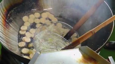 Pirinç krakerleri sıcak yağda cızırdıyor. Geleneksel pişirme işlemi sırasında tavada altın ve çıtır çıtır oluyor.