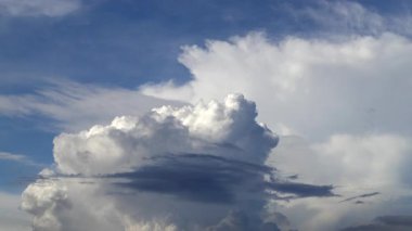 Beyaz bulutların hızlandırılması ve mavi gökyüzünde fırtına bulutları toplamak; tüylü hareket eden bulutlar