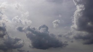 Hareket eden kabarık bulutlar, parlayan güneş ışınları, güneşli bir günde beyaz kümülüs bulutları.