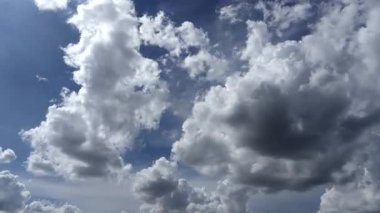 Mavi gökyüzünde hareket eden kabarık bulutlar ve beyaz kümülüs bulutları