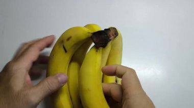 Muzları muz tarağından çıkar. Bir adamın elleri muz soyarken.