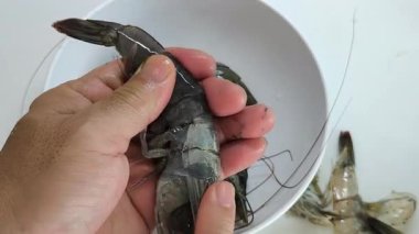 Taze karidesler, bir adam tarafından tek tek, basit bir beyaz kâseye soyuluyor..