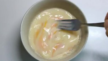 Bir aşçı, karışımı hazırlamak için yumurta ve süt çırpar..