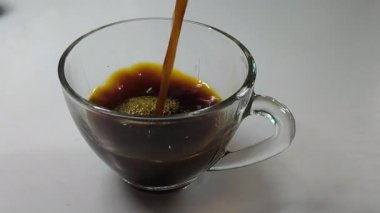 Yakın plan kahvenin çaydanlıktan bekleme bardağına aktığını gösteriyor..
