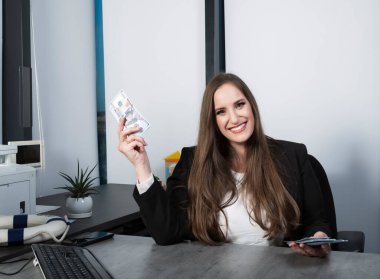 100 dolarlık banknotlar tutan şanslı sarışın kadın para ödülü kazanmak için heyecanlanıyor, zafer ve zenginliği ifade ediyor. Elinde nakit parayla elinde banknotlar olan bir kadın. Banknotları tutan uzun saçlı bir kadın.