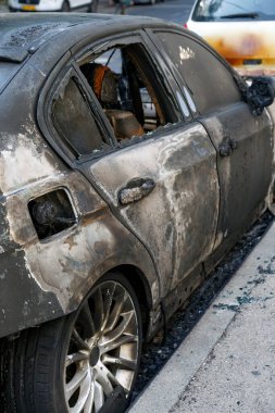 Closeup of a burned out car on roadside down in the middle of the street. Burnt new car, vandalism, mafia. Windows shattered from the explosion.  Setting fire to cars of a terrorist attack on the city